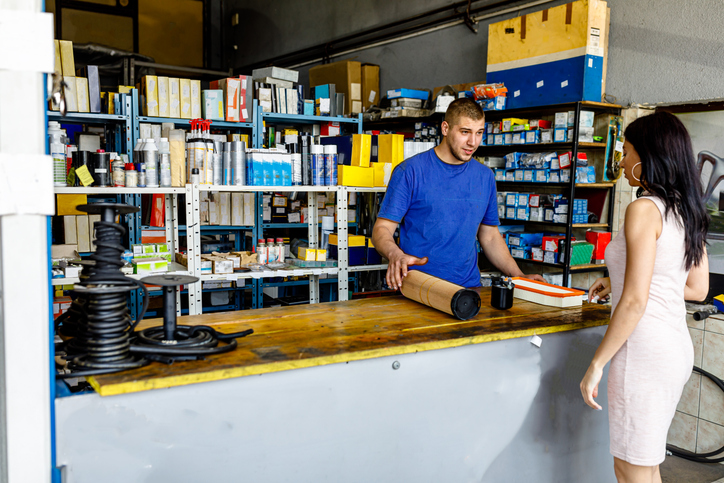 an auto parts store clerk speaks with a young woman