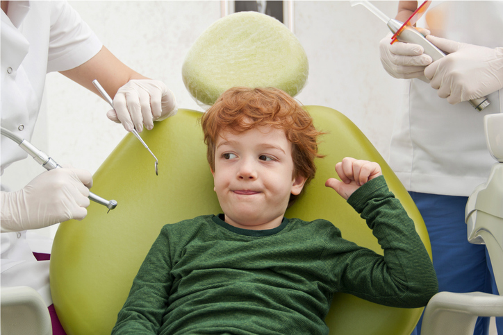 Little cute boy sitting in chair at dentist