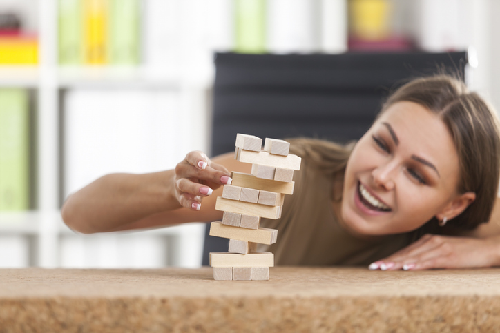 a female using risk management to determine which block to pull from a Jenga-like game