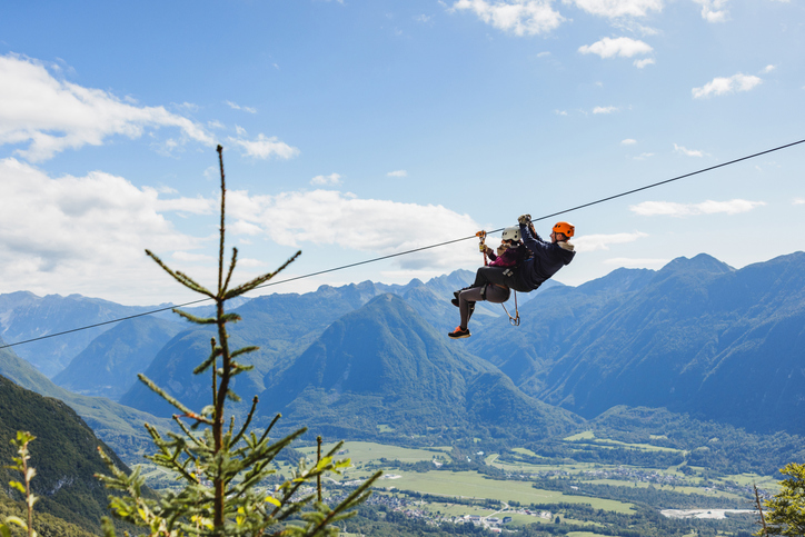 a person dangles from a zip line high above the ground